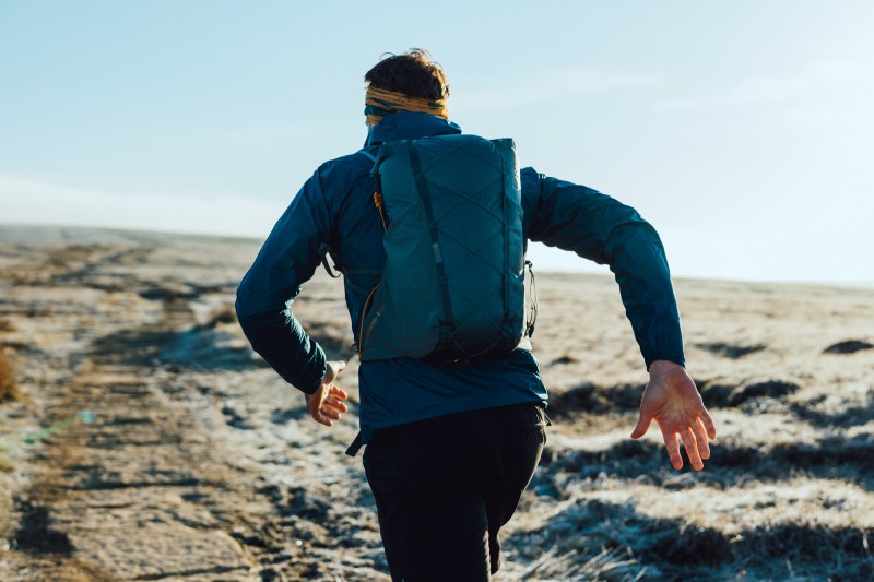 近距离拍到一个人离相机而去穿蓝夹克并背着蓝背包