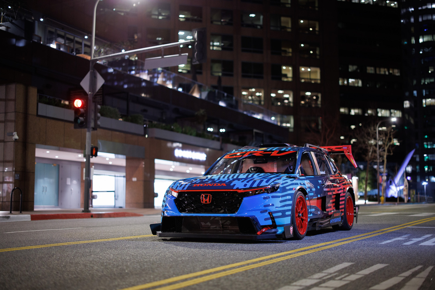 Honda CR-V混合赛车手前端夜间停在街中间高楼前